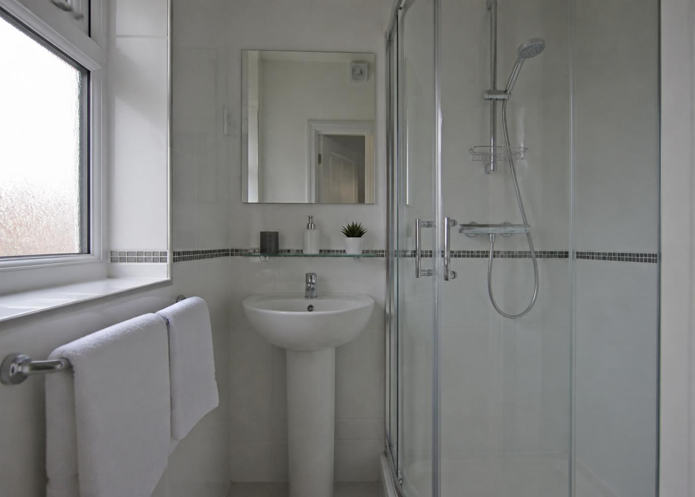 The same bathroom deep cleaned with polished chrome, bright grout and folded towels